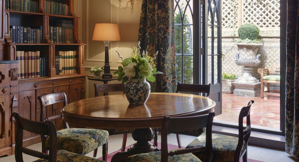 Elegant boutique hotel room with intricate Georgian-inspired decor, rich dark wood furnishings, and luxurious plush bedding in a historic United Kingdom setting