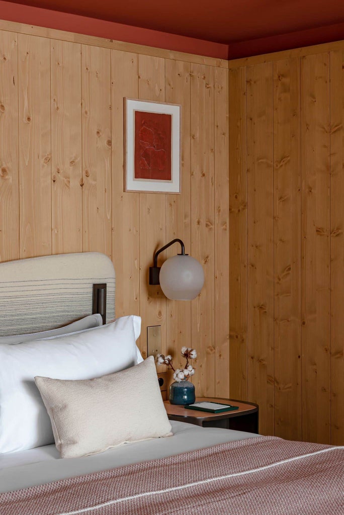 Elegant alpine-style deluxe room at Le Coucou Méribel, featuring warm wood accents, plush bedding, and panoramic mountain views in French ski resort