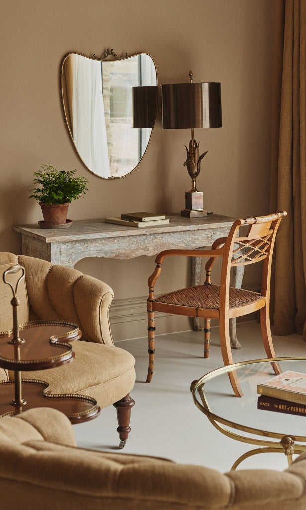 Elegant thyme-green bedroom with plush white bedding, antique wooden furniture, soft natural light filtering through garden-view windows in UK boutique hotel