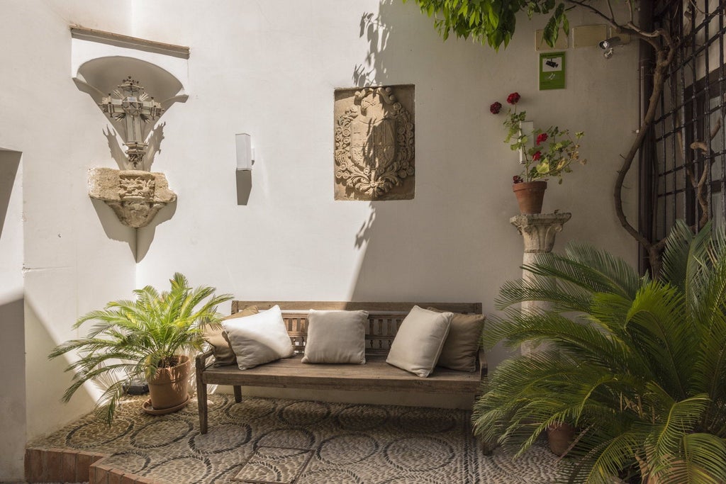 Elegant whitewashed Spanish colonial hotel with intricate balconies overlooking historic Córdoba's charming cobblestone streets and traditional architectural details