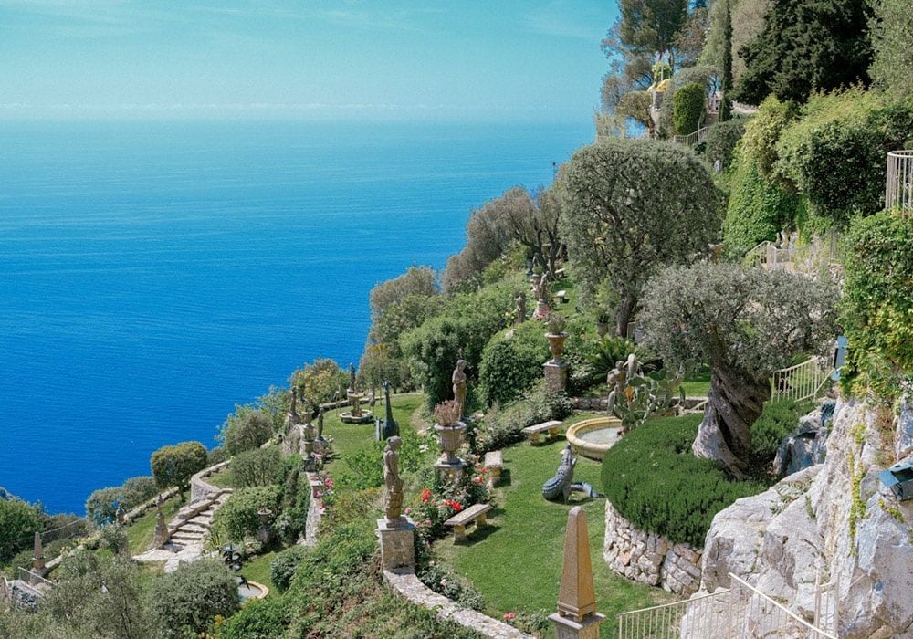 Mediterranean luxury hotel Le Chevre d'Or perched on cliffside with panoramic views of French Riviera coastline and azure waters below