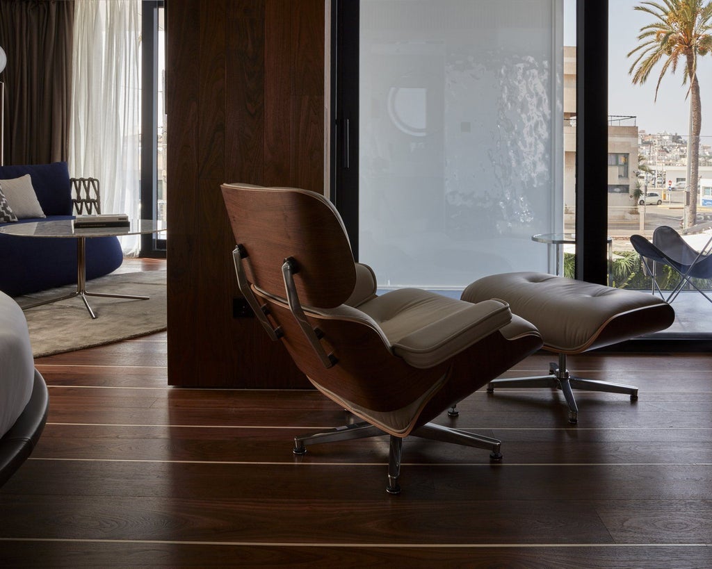 Modern minimalist luxury hotel room with white and wood tones, expansive city view, sleek design, elegant furnishings, and floor-to-ceiling windows at Sir Joan Hotel in Spain