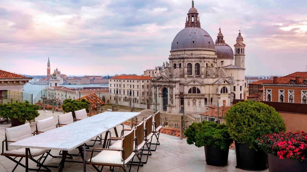 Opulent 1-bedroom suite with ornate gold decor, crystal chandelier, marble columns and panoramic Venice canal views through tall windows