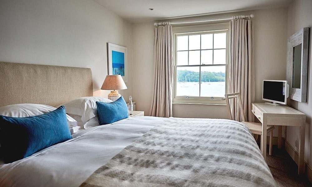 Luxurious seaside hotel room with panoramic ocean views, crisp white linens, coastal-inspired decor, and expansive windows overlooking the scenic UK coastline