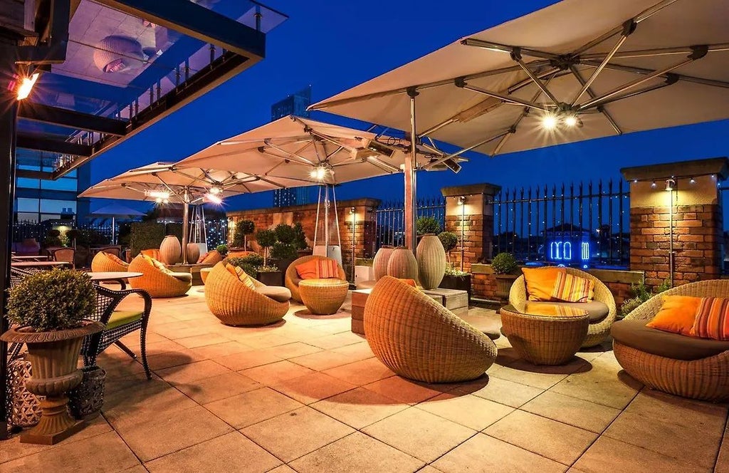 Boutique luxury hotel exterior with elegant red brick facade, large windows, and sophisticated urban architectural design in Manchester city center