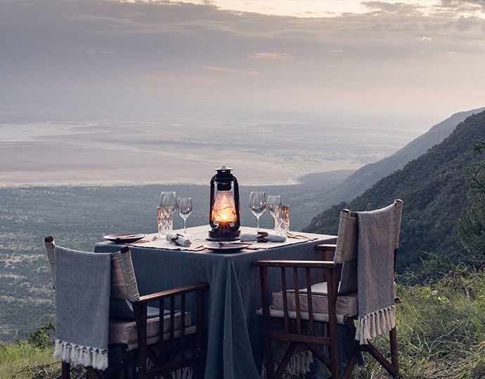 Luxury safari tent with private deck overlooking vast African savanna, featuring canvas walls, wooden floors and elegant outdoor furnishings