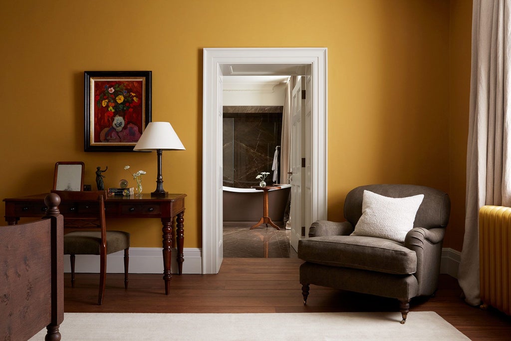 Luxurious ochre-toned hotel room at Heckfield Place, featuring elegant minimalist design with warm textiles, soft lighting, and sophisticated rural UK aesthetic