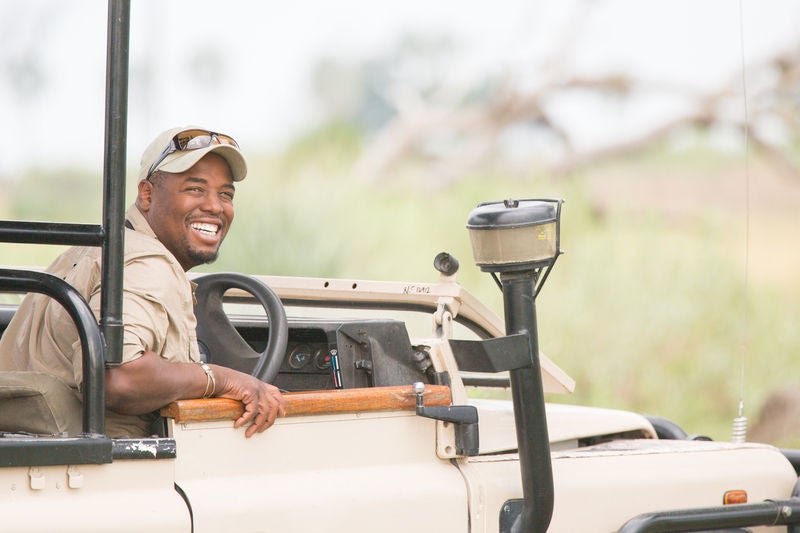 Luxury safari tent overlooking Botswana's Okavango Delta, with wooden deck, canvas walls, and natural surroundings at sunset