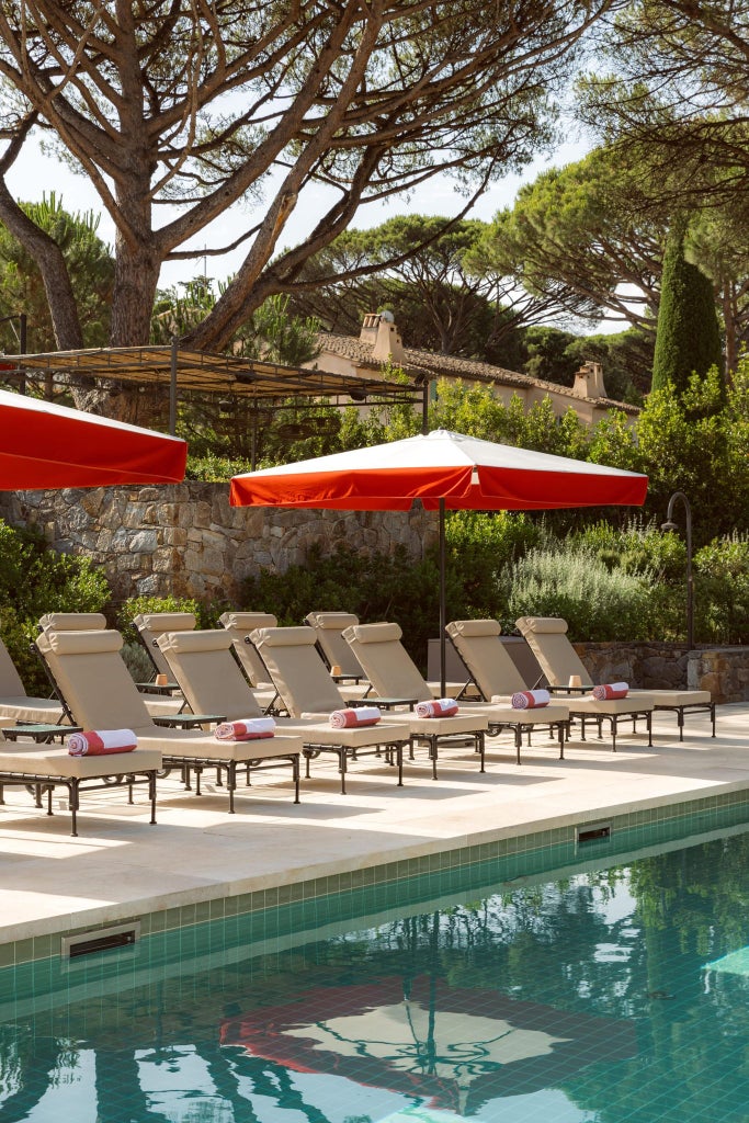 Luxurious swimming pool at Hotel Scenset in Saint-Tropez, surrounded by lush Mediterranean gardens and elegant sunbeds with pristine blue water.