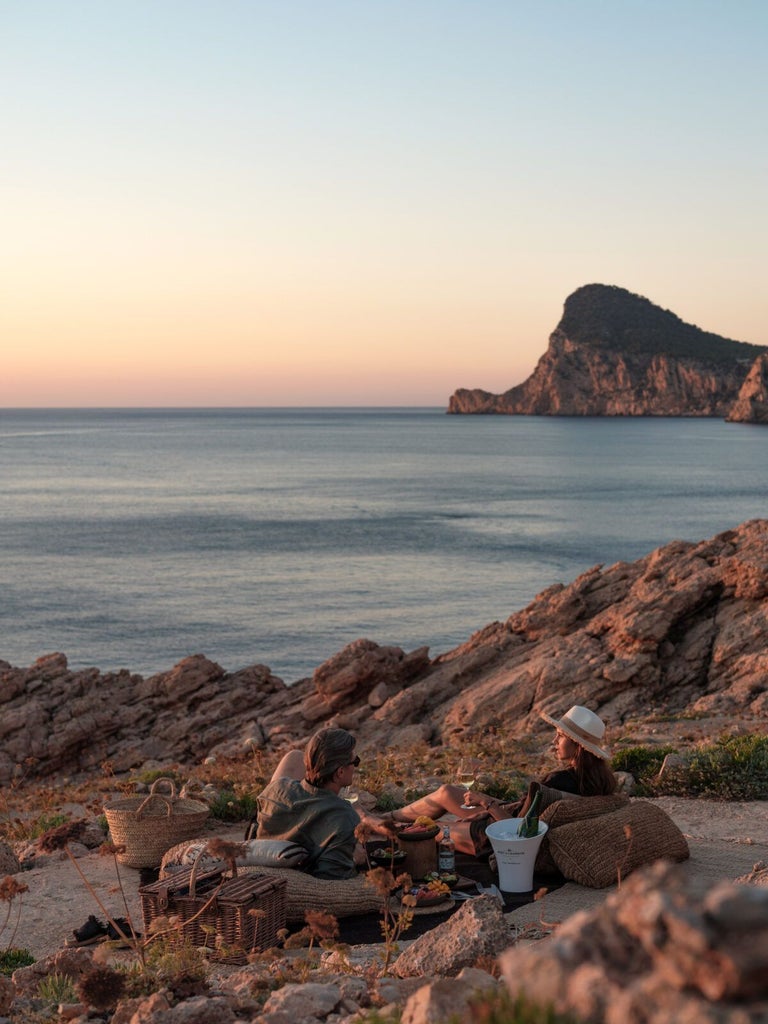 Luxurious white-washed Balearic hotel exterior with minimalist design, infinity pool overlooking Ibiza's azure coastline at golden sunset