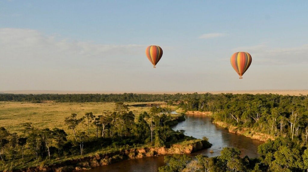 Luxurious safari tent overlooking Mara plains at sunset, with canvas walls, wooden deck and traditional African furnishings