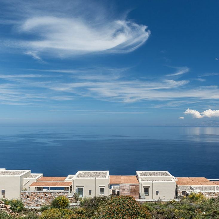 Luxurious whitewashed Cycladic hotel overlooking azure Aegean Sea, with minimalist design, infinity pool, and stunning sunset views at Scenset Astra.