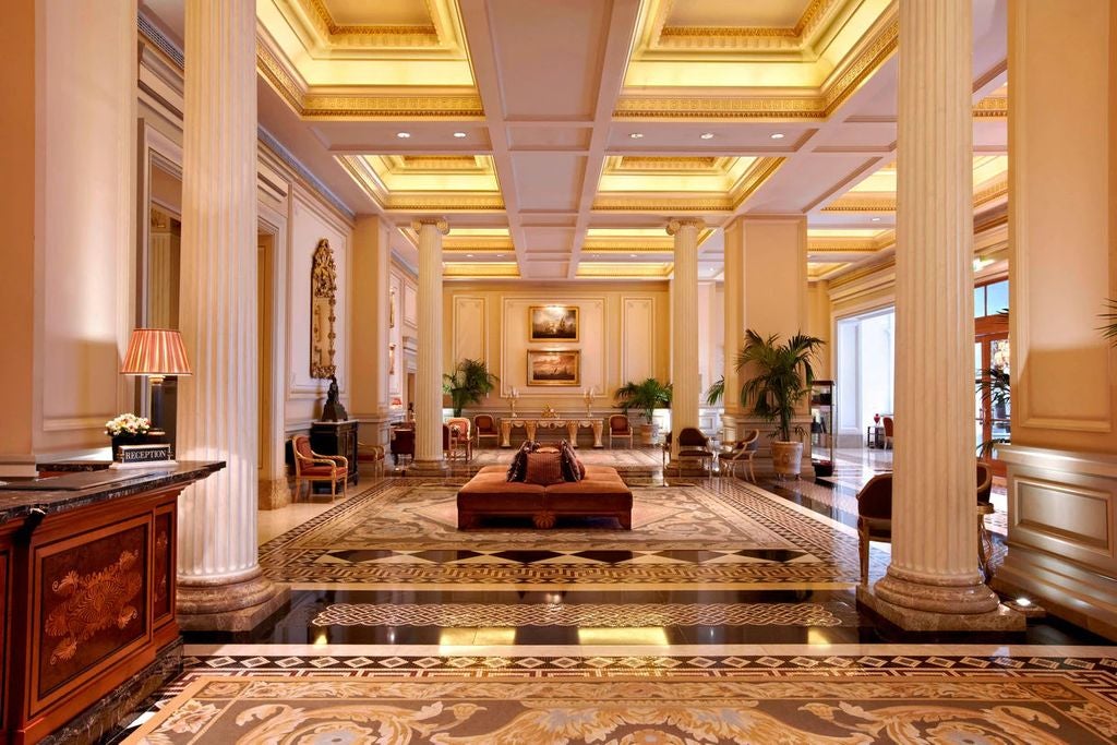 Historic Hotel Grande Bretagne building in Athens, with neoclassical architecture, ornate balconies, and cream-colored facade lit by warm evening light