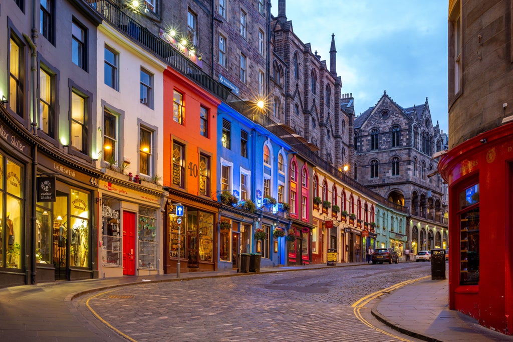 Historic Edinburgh castle perched on rocky hill, golden sunlight illuminating medieval stone walls with lush green landscape stretching below scenic Scottish cityscape