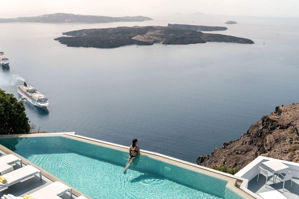 Whitewashed cliffside hotel with infinity pool overlooking Santorini's caldera, Mediterranean Sea and sunset views, private terraces