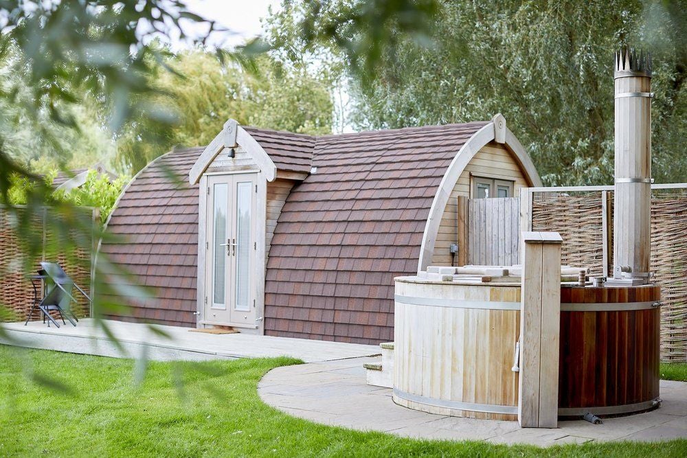 Luxurious rustic hotel room at Tuddenham Mill with soft neutral tones, plush bedding, wooden accents, and charming countryside view through large windows