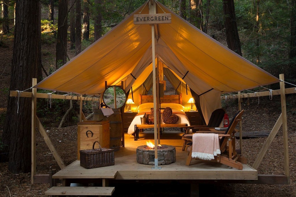 Luxurious safari-style tent nestled among towering redwoods, featuring a private deck and upscale outdoor furnishings at Ventana Big Sur