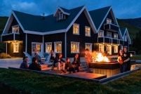 Luxurious Icelandic manor hotel nestled in verdant countryside, with traditional turf-roofed architecture against dramatic mountain and green meadow backdrop