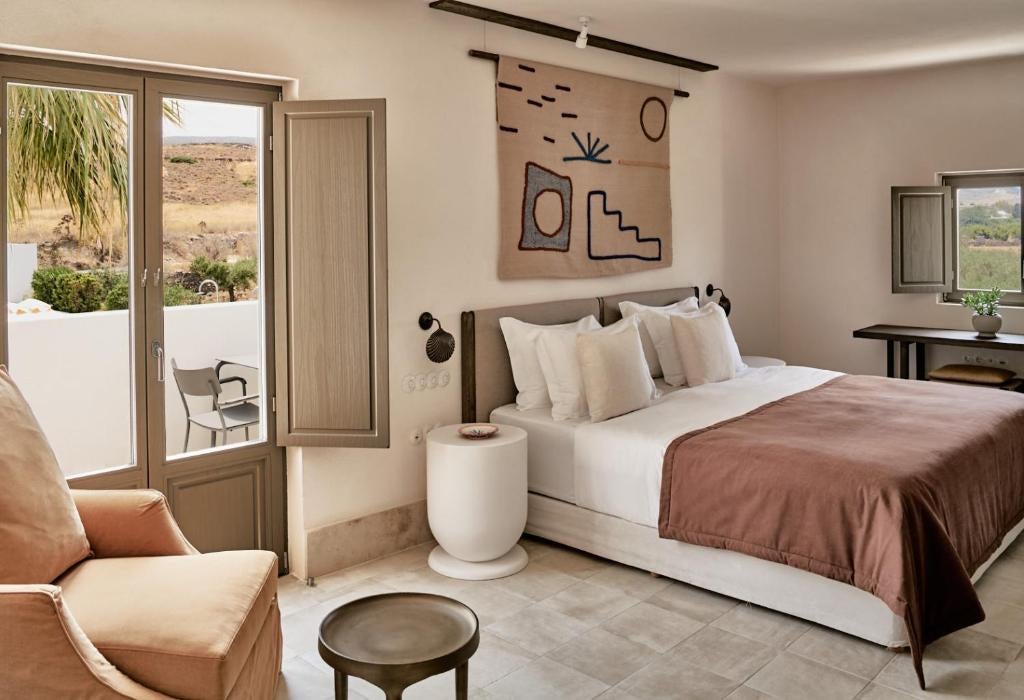 Modern luxury hotel entrance with white stone archways, minimalist Mediterranean architecture, geometric shadows and desert plants