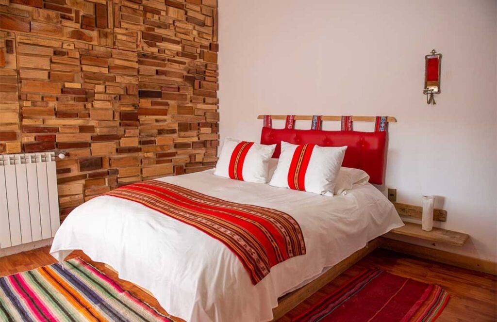 Spacious superior triple hotel room with minimalist design, warm earth tones, and large windows overlooking scenic Bolivian landscape at Flamencos Altiplano Eco-Hotel