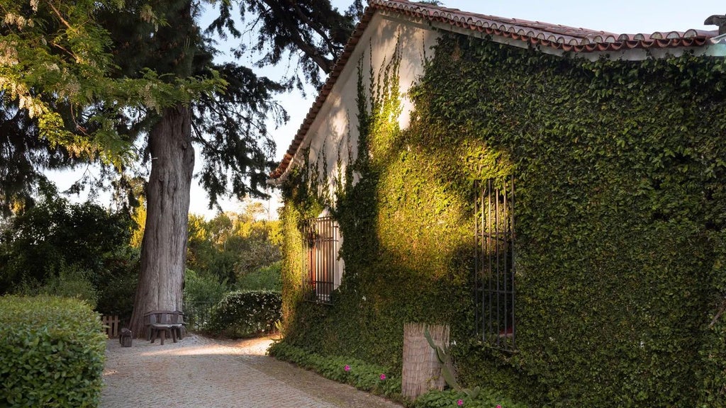 Rustic stone farmhouse nestled in Portuguese countryside, with elegant terracotta roof, lush gardens, and rolling hills creating a serene luxury retreat landscape