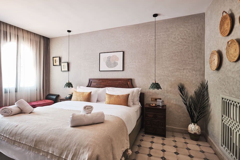 Elegant Moroccan bedroom with ornate brass lamp, draped canopy bed, handwoven rugs, and traditional carved wood furnishings