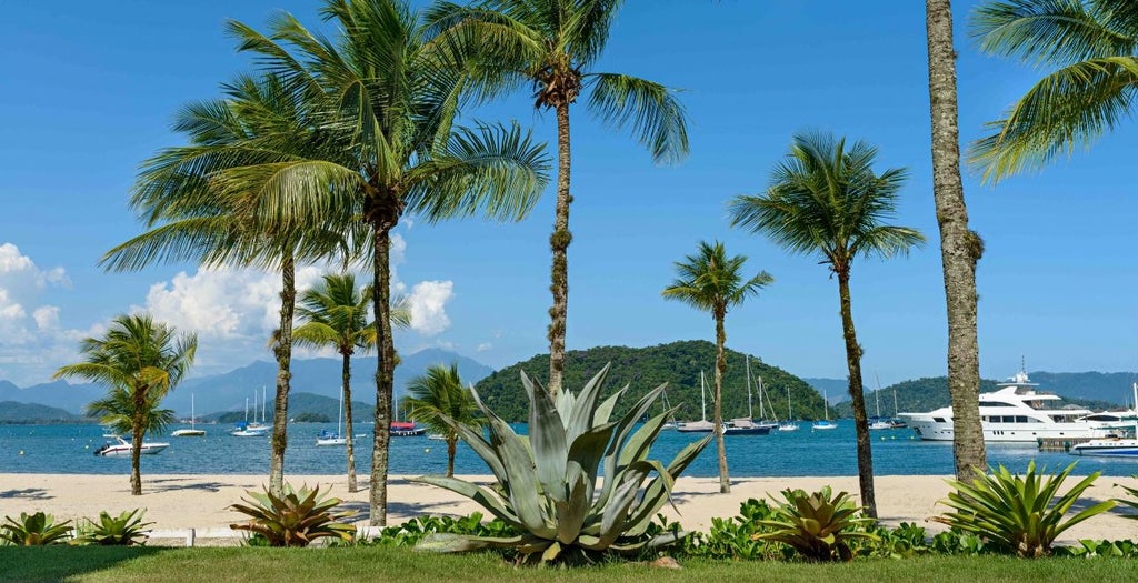 Modern seaside resort with infinity pool overlooking turquoise ocean bay, private marina, and lush mountains in Angra dos Reis, Brazil