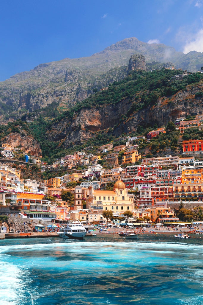 Elegant cliffside houses in pastel colors cascade down Amalfi Coast's rugged terrain, overlooking turquoise Mediterranean waters