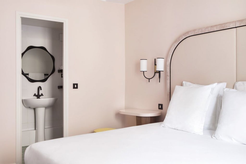 Elegant Parisian hotel room with soft cream walls, plush white bedding, vintage wooden furnishings, and warm ambient lighting creating a cozy, intimate atmosphere