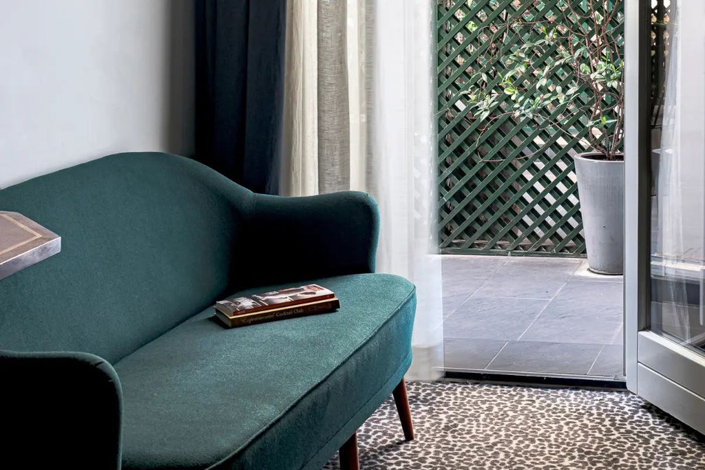 Elegant Parisian hotel room with soft color palette, featuring plush bedding, vintage-inspired decor, and large windows with warm golden light