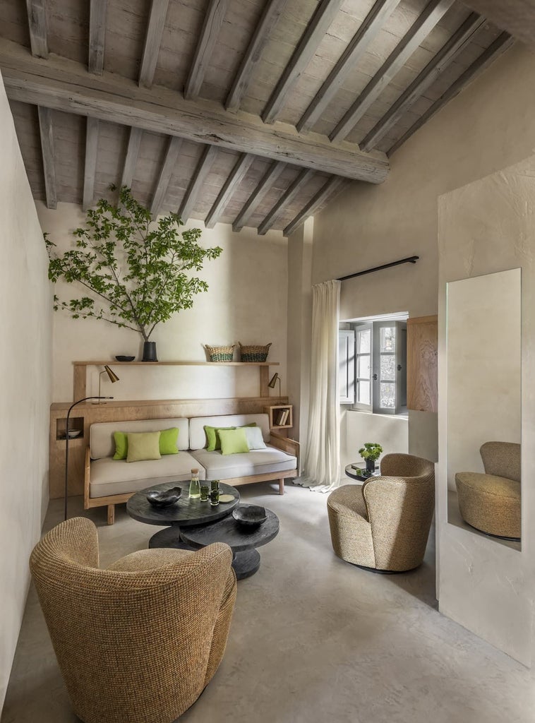 Elegant Italian junior suite with rustic wood ceiling, plush white linens, and warm terracotta-toned walls overlooking Tuscan landscape at Badia di Pomaio