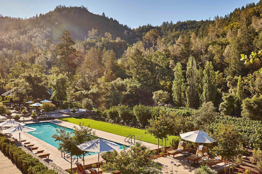Luxurious mountain resort lodge with stone facade nestled among lush oak trees, featuring rustic wood beams and floor-to-ceiling windows