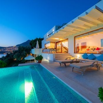 Luxurious Turkish villa bedroom with panoramic sea view, featuring elegant white linens, wooden furniture, and open balcony overlooking turquoise coastline