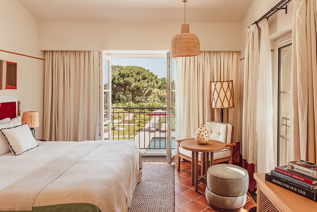 Elegant superior room at Lou Pinet hotel, featuring soft neutral tones, plush bedding, contemporary French design with minimalist wooden furniture and warm lighting