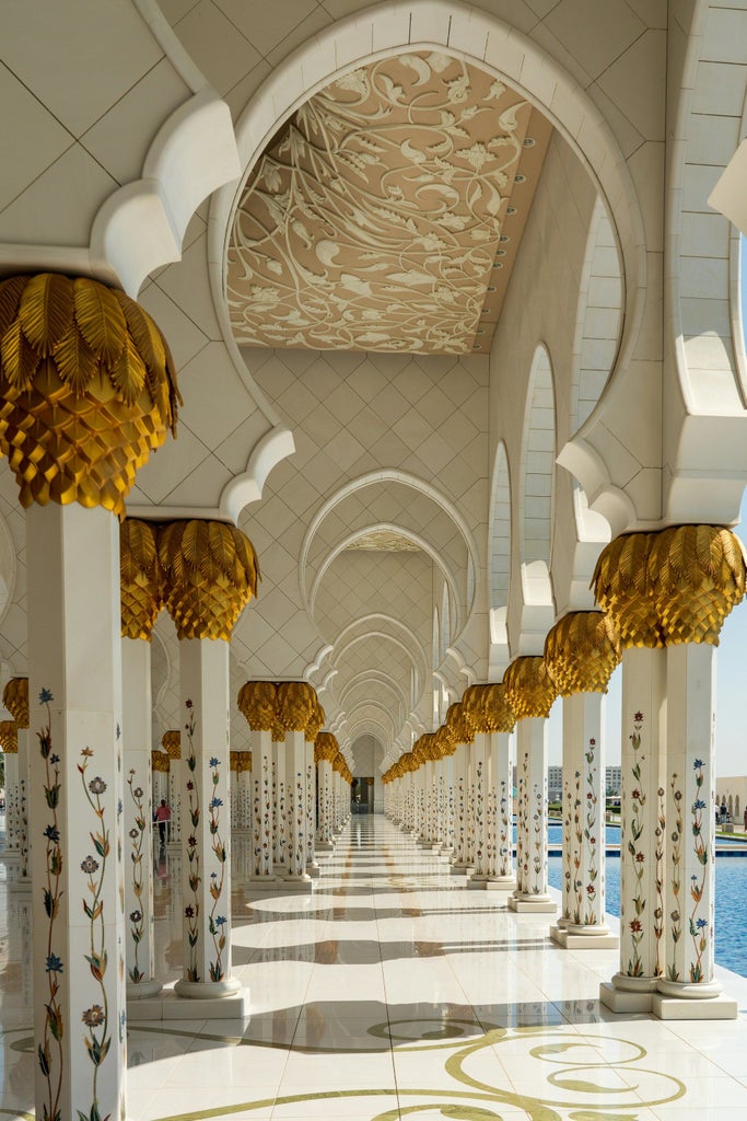 Seven-star Emirates Palace Hotel exterior view with golden domes, palm trees, and manicured gardens under bright Abu Dhabi sunlight