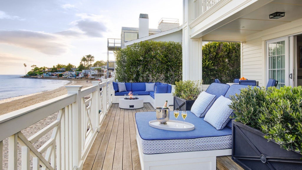 Luxurious beachfront terrace suite with panoramic ocean view, elegant outdoor seating, and modern coastal design at a high-end resort