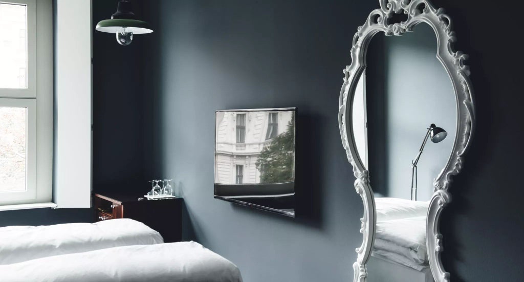 Elegant Viennese hotel room with plush white bedding, classic wooden furnishings, soft neutral color palette, large window revealing Austrian cityscape