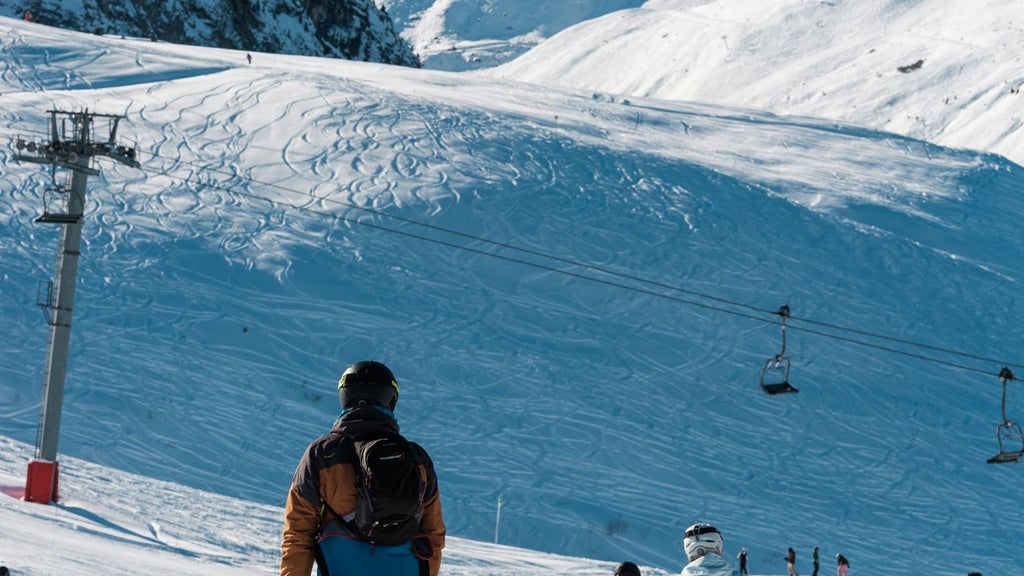 Luxurious alpine hotel nestled in French mountain landscape with snow-capped peaks, elegant wooden chalet-style architecture, and inviting outdoor terrace at scenset.