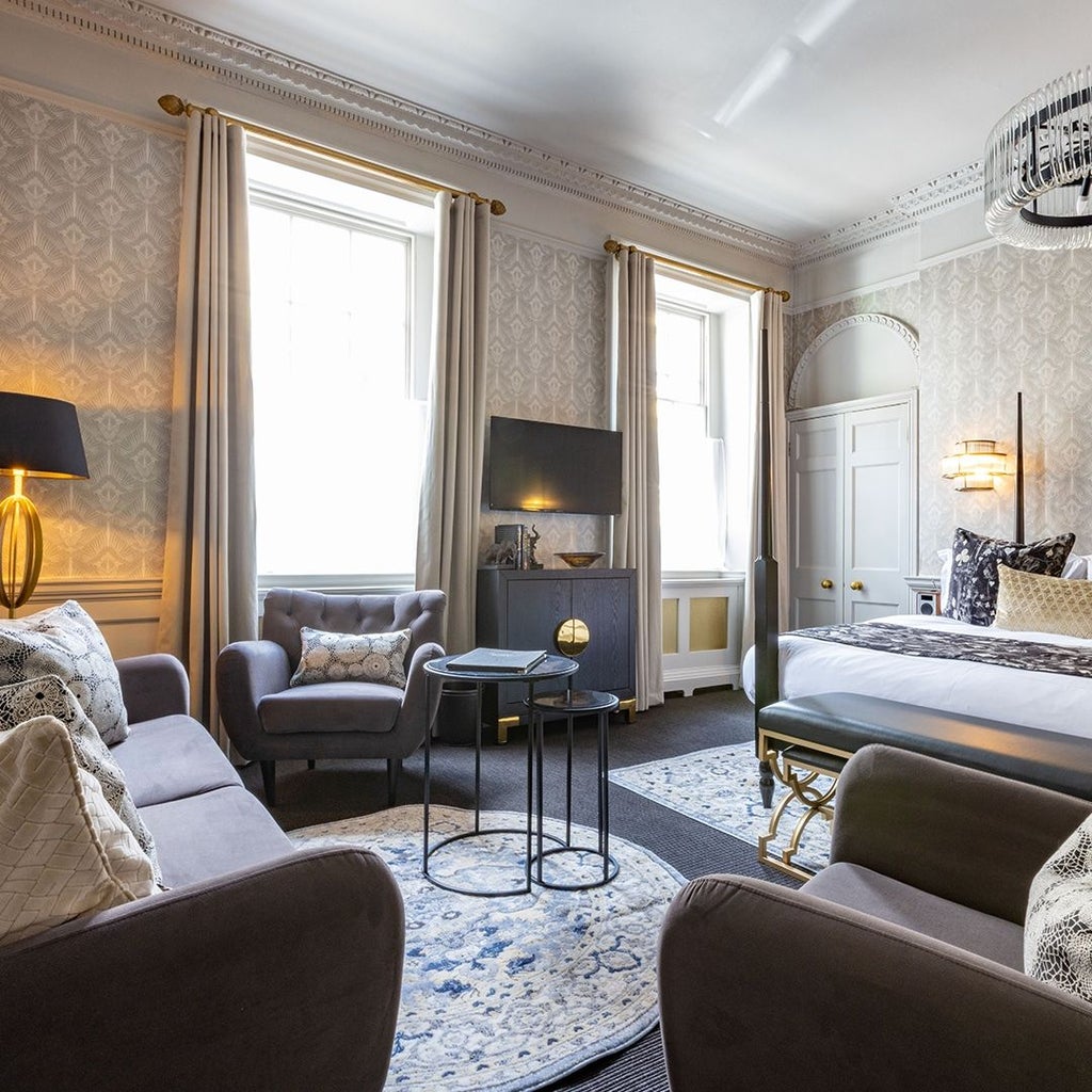 Elegant four-poster bed with rich textiles, soft lighting, and luxurious decor in a spacious period suite at a boutique UK hotel