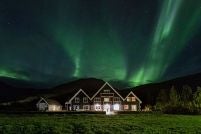 Luxurious Icelandic manor nestled in verdant landscape, stone and wood exterior with dramatic mountain backdrop and lush green surroundings