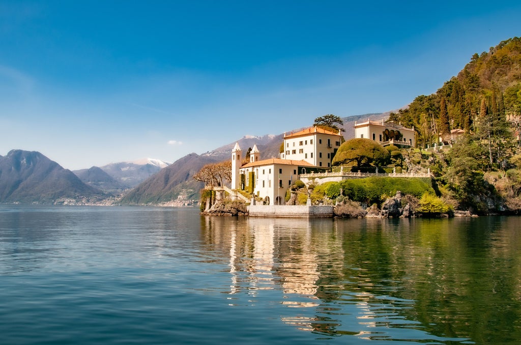 Luxurious waterfront villas nestled along Lake Como's mountainous shoreline, with elegant gardens and boats dotting the tranquil blue waters