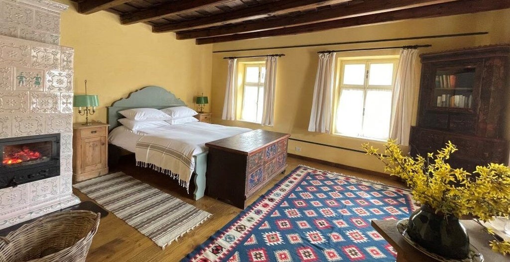 Sunlit yellow luxury suite with elegant wooden furnishings, plush white linens, and warm Romanian architectural details in a charming coastal guesthouse