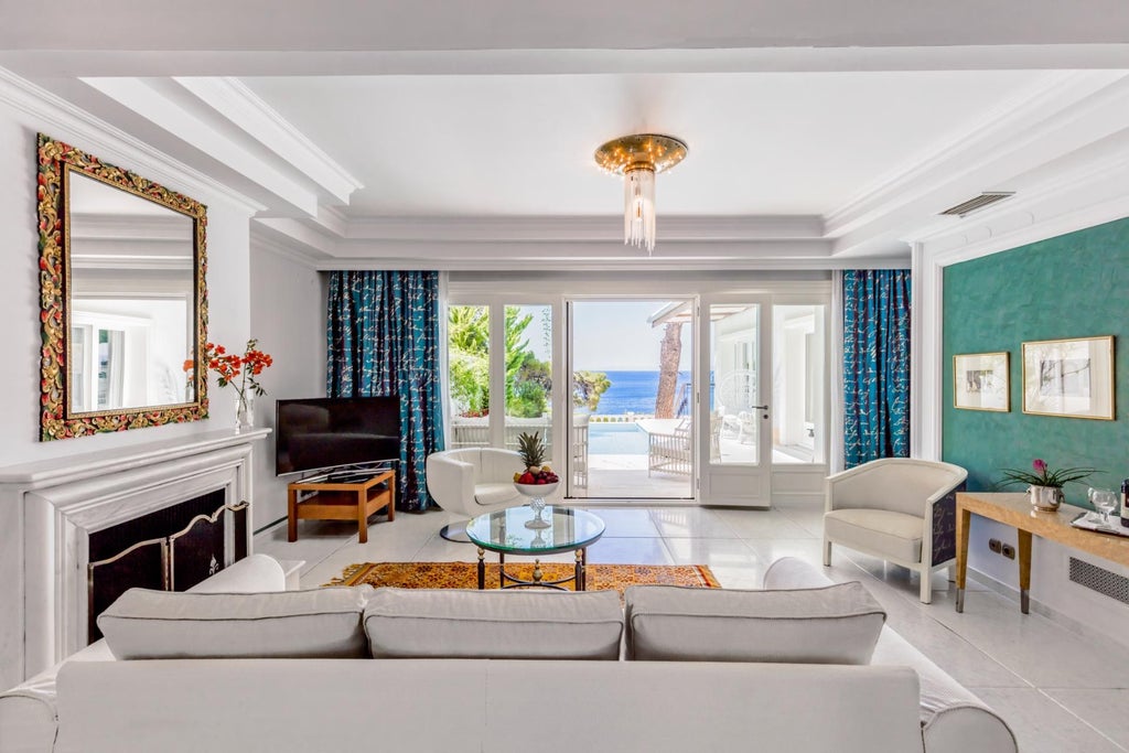 Luxurious beachfront villa with expansive sea view, elegant white interiors, private balcony, and direct access to turquoise waters of Greek coastline