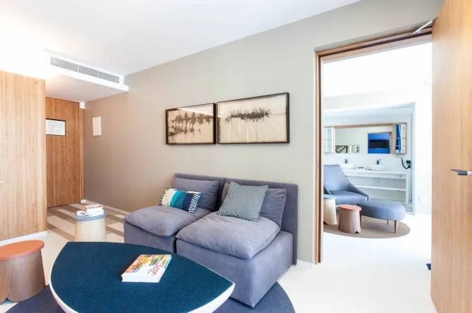 Modern junior suite with white minimalist decor, ocean view, large sliding glass doors, king bed, and contemporary design overlooking Talamanca's coastal landscape in Spain