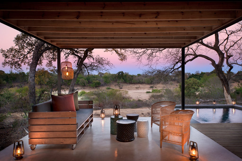 Modern private villa balcony overlooking African savanna, featuring infinity pool and luxurious outdoor lounge with pristine wilderness views