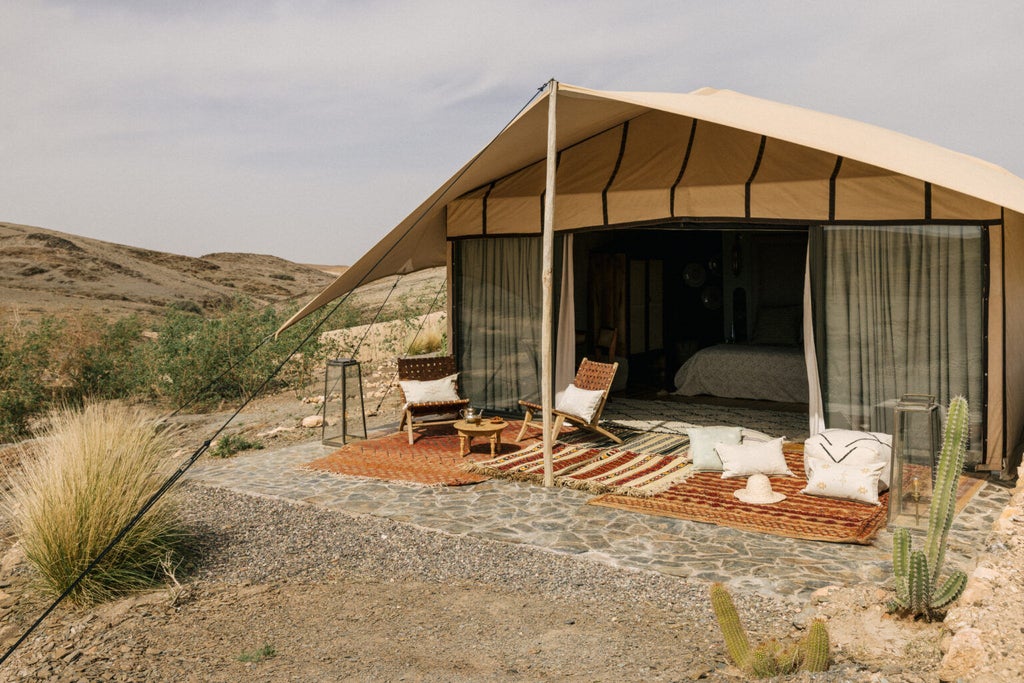 Luxurious desert lodge tent with panoramic windows, modern furnishings, and Atlas Mountains views, set in Morocco's Agafay Desert