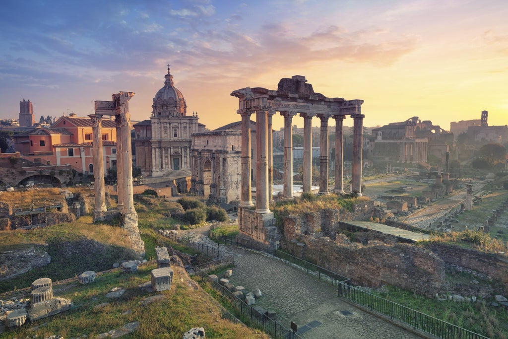 Iconic Colosseum in Rome at sunset with golden light illuminating ancient stone arches, set against a vibrant orange and purple sky