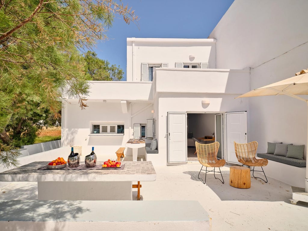 Elegant stone villa overlooking azure Aegean waters, surrounded by lush Mediterranean landscape with classic Greek architectural design and terracotta rooftops