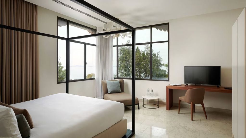 Luxurious hotel villa room with modern decor, king bed, marble floors, floor-to-ceiling windows overlooking Venice lagoon and gardens