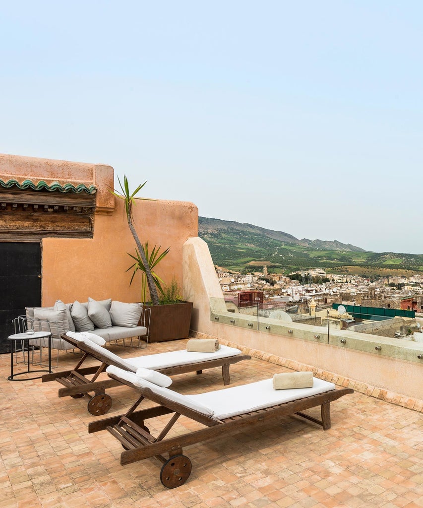 Luxurious traditional Moroccan riad with intricate blue ceramic tiles, ornate archways, and elegant courtyard featuring a decorative fountain at Hotel Scenset Fès